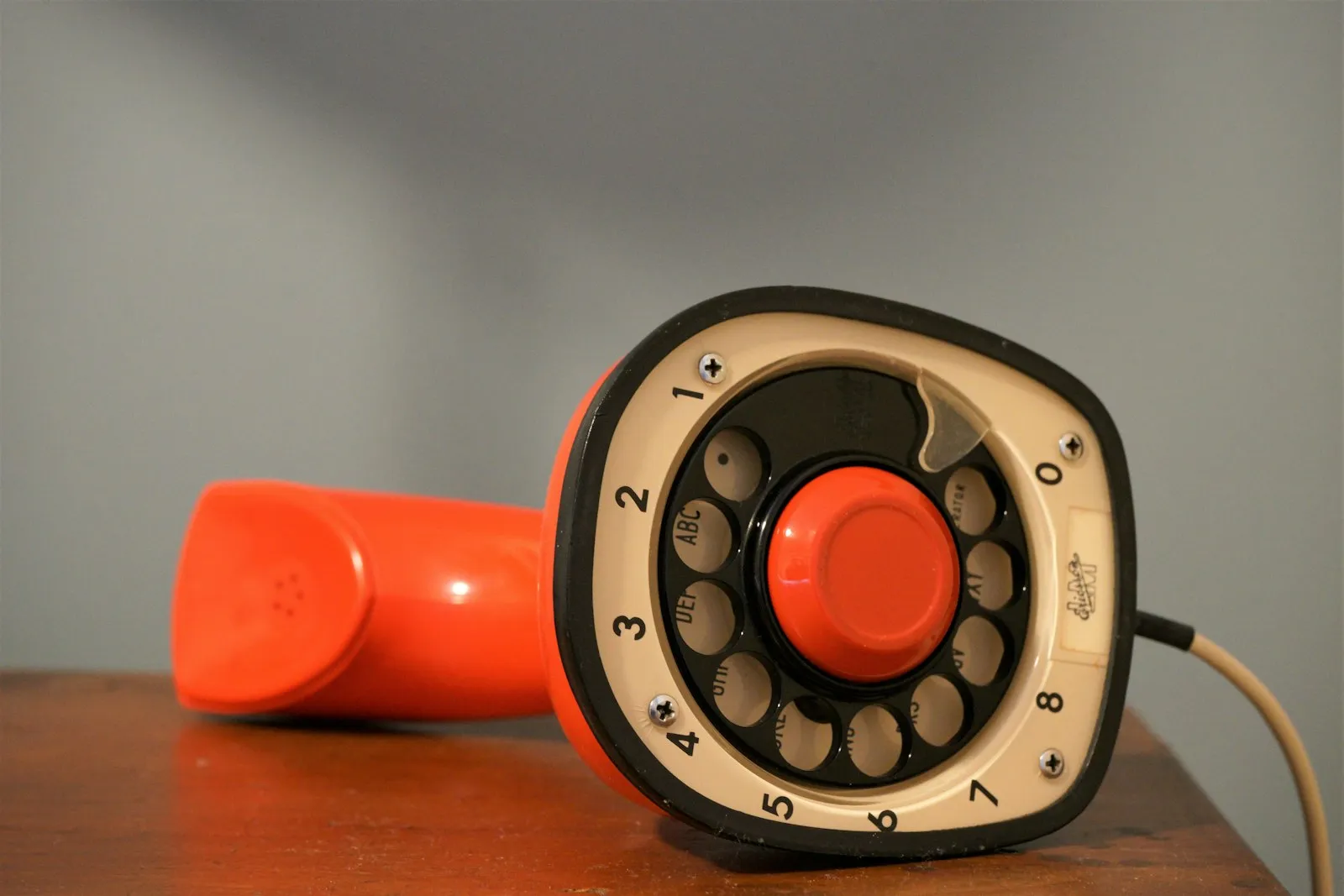 an orange and black telephone sitting on top of a wooden table